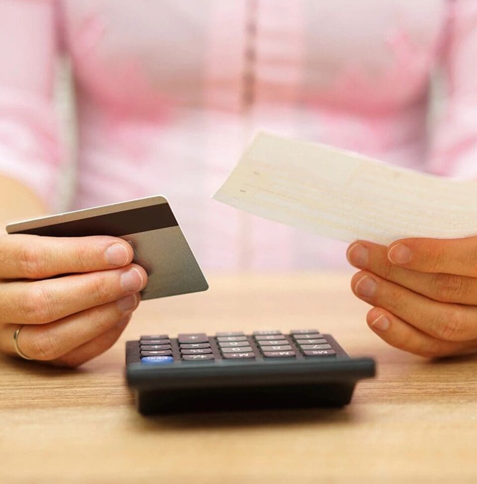 A person holding a credit card and paper